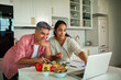 © Marko Geber - Couple preparing vegetables while following an online recipe in a home kitchen