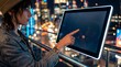 © TRIA - Young woman using interactive kiosk screen with city night lights background