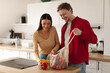© Home-stock - Young couple unpacking fresh groceries from reusable mesh bag in kitchen