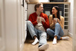 © Home-stock - Happy young couple sitting on kitchen floor holding coffee mugs