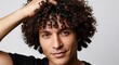 © Владимир Platon - Close-up shot of a cheerful man with dense curly hair smiling gently while touching his hair with his hand