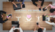 © InfiniteFlow - Group of Diverse People Engaging in Discussion on Resilience and Mindset with Various Devices on a Wooden Table Haptic.
