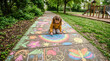 © INT888 - Girl drawing concrete path chalk child sidewalk rainbow park playground girl drawing concrete path with colorful chalk, cheerful creativity beside green tree, grass, flower, sun, butterfly