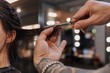 © Yohanessoekamti - Professional hairstylist trimming long dark hair with precision scissors in a well-lit salon, close-up shot showcasing expert haircut technique and client service