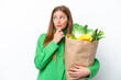 © luismolinero - Young caucasian woman holding a grocery shopping bag isolated on white background and looking up