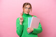© luismolinero - Young caucasian student woman isolated on pink background with fingers crossing and wishing the best