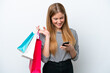 © luismolinero - Young caucasian woman isolated on white background holding shopping bags and writing a message with her cell phone to a friend