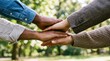 © PixelDust_ - People join hands in a park on a sunny day showing unity and support among diverse individuals.