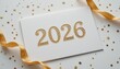 © Genzinix - Shiny gold 2026 numbers printed on white paper card with elegant ribbons and festive star confetti