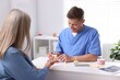 © New Africa - Doctor consulting woman regarding dental implantation at desk in clinic