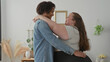 © Krakenimages.com - Plus size woman smiling hugs man, arms around his neck and hand on waist, denim jacket and hanging plants visible in studio; love togetherness.