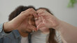 © Krakenimages.com - Woman forms heart with hands with man partner in building, ring on finger visible; affection together.