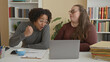 © Krakenimages.com - Man and woman leaning over laptop at desk with clipboard, coffee cup and stacked folders, man making a fist gesture while studying the screen in a building; collaboration concentration.