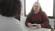 © Krakenimages.com - Woman holding paper receiving a prescription from doctor across a clinic desk in a medical building; concern trust.