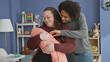 © Krakenimages.com - Plus size woman cradles swaddled baby while father embraces from behind in nursery with toys and shelf visible; family love.