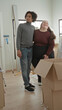 © Krakenimages.com - Man and plus size woman stand close, his arm around her waist, she points toward a sunlit window beside open moving boxes and scattered packing peanuts in a building; moving day joy.