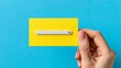 © InfiniteStudio - Hand holds yellow job search card with search bar against blue background for recruitment use