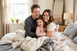 © Meow Creations - Happy parents and daughter hugging and laughing on a bed