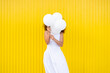 © VISTA by Westend61 - Female hiding face behind white balloon on yellow background
