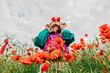 © VISTA by Westend61 - Woman in retro tracksuit covers eyes with red poppies in a meadow