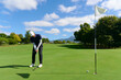 © khmelev - Man putting golf ball on green golf course