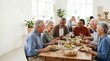 © Xenia - Diverse group of senior friends sharing a meal at a table. Happy elderly people eating together indoors