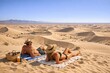 © Fotograf - A couple relaxing on a blanket in the desert, enjoying the scenery