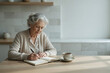 © Neural Canvas - Senior woman writing journal elderly lady notebook peaceful morning light cozy kitchen table warm sweater cup of coffee quiet reflection calm mood the concept of Digital detox lifestyle