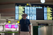 © Nazareno - Traveler checking flight information at airport terminal