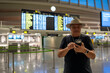 © Nazareno - Tourist in airport terminal checking flight information on smartphone