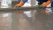 © Fahroni - Mason worker working with trowel to level cement floor at construction site. A skilled construction worker spreading wet concrete to level wet concrete on a site floor. Foundation and flooring tasks.