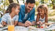 © Olya Pilipchik  - Father and his two happy daughters enjoying a summer picnic in a lush park, bonding while sharing food and refreshing drinks on a sunny day outdoors