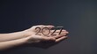 © Helen - A pair of cupped human hands holding metallic numbers representing the year twenty twenty seven with a target symbol integrated into the central zero