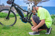 © luciano - Senior man in helmet tying shoelace, preparing for electric bicycle ride along the beautiful coast, enjoying an active outdoor retirement lifestyle on a sunny day