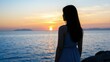 © CrazyJuke - A Lone Soul Gazing at the Horizon: A woman stands silhouetted against a breathtaking sunset over the ocean, her gaze fixed on the distant horizon, evoking a sense of contemplation and wonder.