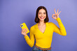 © deagreez - Young chic student smiles and poses with yellow phone against purple background showcasing fashion style and modern lifestyle