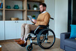 © Seventyfour - Caucasian young adult man with disability using tablet while sitting in wheelchair at home, managing digital tasks and independent living. Ideal for accessibility, remote work, inclusion