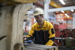 © FotoArtist - Worker in safety gear operates machinery inside a workshop during daylight hours