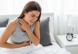 © twilight mist - Young Woman Suffering from Stomach Ache and Sore Throat Sitting on Bed in the Morning - Health Problems Concept