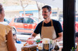 © Milles Team/Stocksy - Smiling waiter serving his guests at cafe