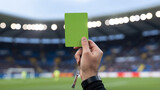 Green referee card held in hand stadium background soccer football