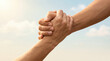 © Creative Valley - Close up of two hands clasped together in a supportive grip against a bright sky, celebrating trust, friendship, unity, encouragement, hope, lasting human connection and Friendship Day concept