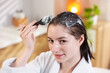 © New Africa - Woman applying mask onto her hair in bathroom