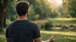© olga_demina - A man sits cross-legged in a meditative position on the green grass of a park, bathed in warm, natural sunlight with lush trees nearby