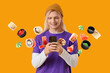 © Pixel-Shot - Young man using smartphone with floating sushi pieces on orange background