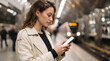 © ViskBx - Young woman looking at her smartphone while waiting for a train at a subway station