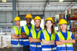 © ultramansk - Multiethnic group of male and female logistics employees in protective workwear pose for a team portrait among the pallet racks in a spacious logistics centre filled with shrink wrapped.