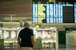 © Nazareno - Traveler checking flight information board in airport terminal