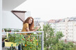 © Westend61 - Smiling woman with cup of coffee on balcony