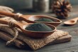 © DriftPixels - Spirulina Powder in Wooden Spoons Close Up on Rustic Tabletop Healthy Eating Concept Still Life